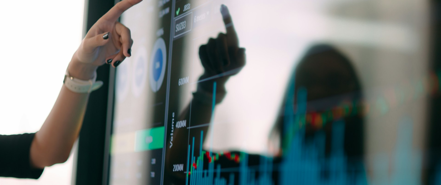 A woman's hand points to a screen with a predictive analysis dashboard.